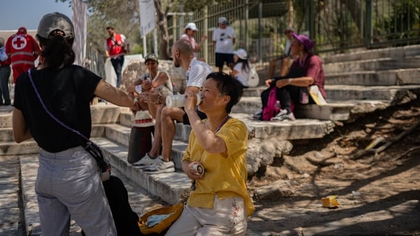 A tourist drinks water outside of the closed Acropolis Hill monument site in Athens during a heatwave