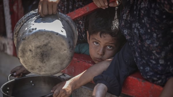 A child holds a pan to receive food distributed by a charity in Gaza city