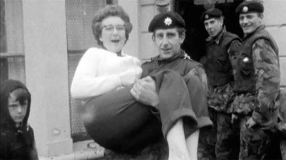 Following a storm, British troops evacuate a woman from her flood-damaged home in Belfast in 1970.