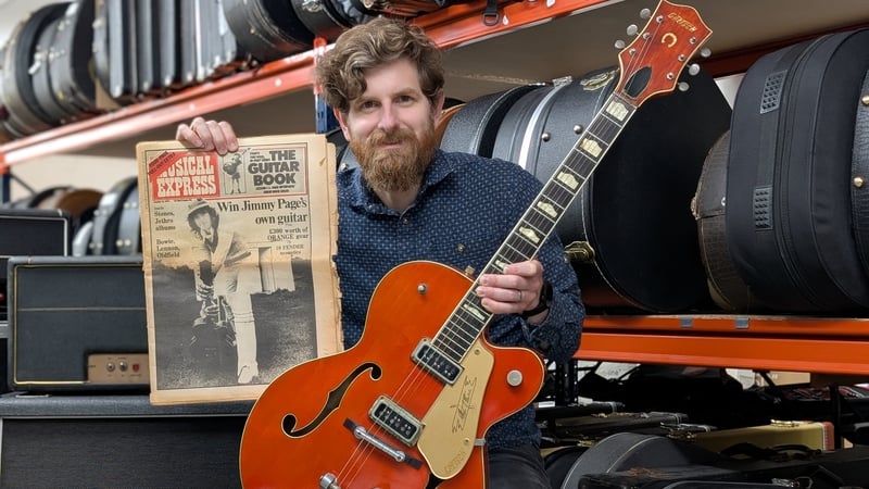 Auctioneer Luke Hobbs, holding a 1957 Gretsch Chet Atkins 6120 electric guitar owned by Led Zepplin's Jimmy Page