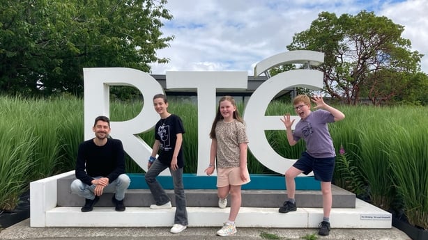 a group of people posing for a photo in front of the RTÉ sign