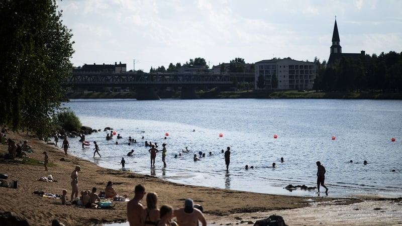 People enjoy the warm weather at the Ounaskoski Beach at the Arctic Circle in Rovaniemi, Finnish Lapland