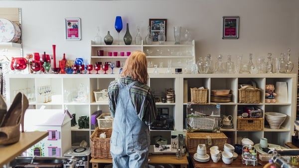a person standing in a room with shelves and vases