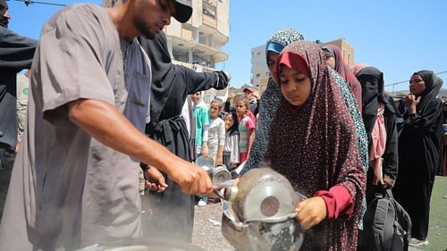 Hundreds of Palestinians struggling with hunger have to wait in line for hours under the scorching heat to receive food aid