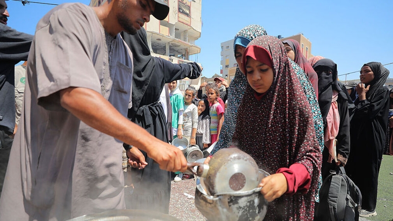 Hundreds of Palestinians struggling with hunger have to wait in line for hours under the scorching heat to receive food aid