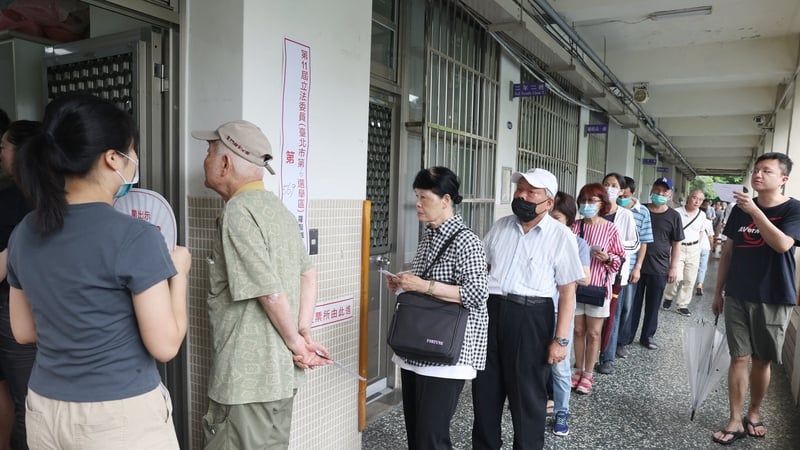 Voters wait in line to cast their ballots at a polling station during the recall election in Taiwan