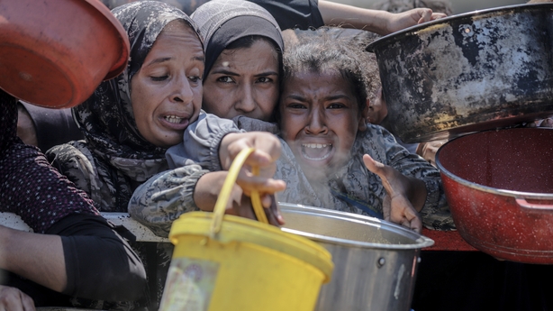 Palestinians gather in long queues under scorching heat to receive food in Gaza City