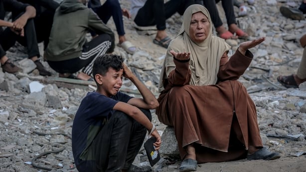 A child and mother sit on rocks in gaza