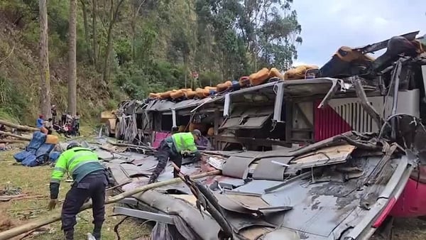 men wearing hi visibility clothing clean up wreckage of a bus crash in Peru with forestry in the background