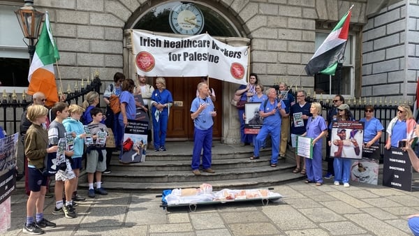 A group of doctors stage a protest wearing personal protective clothing in Dublin with Palestinian flags behind them