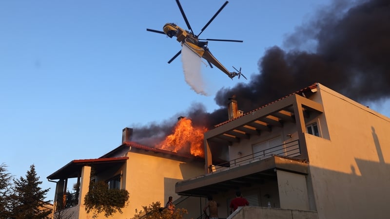 Smoke and flame rise as firefighting teams respond from the air and on the ground to a forest fire that broke out in Krioneri near Athens