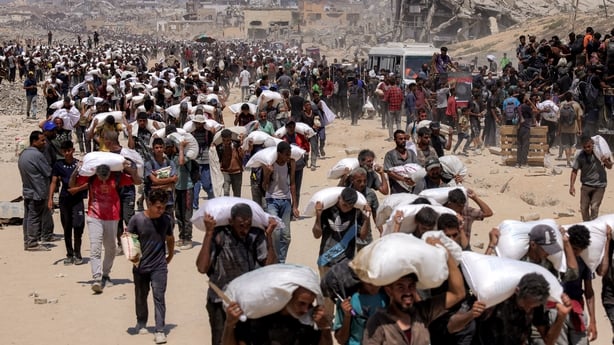 People walk with sacks of flour delivered after trucks carrying humanitarian aid entered northern Gaza 
