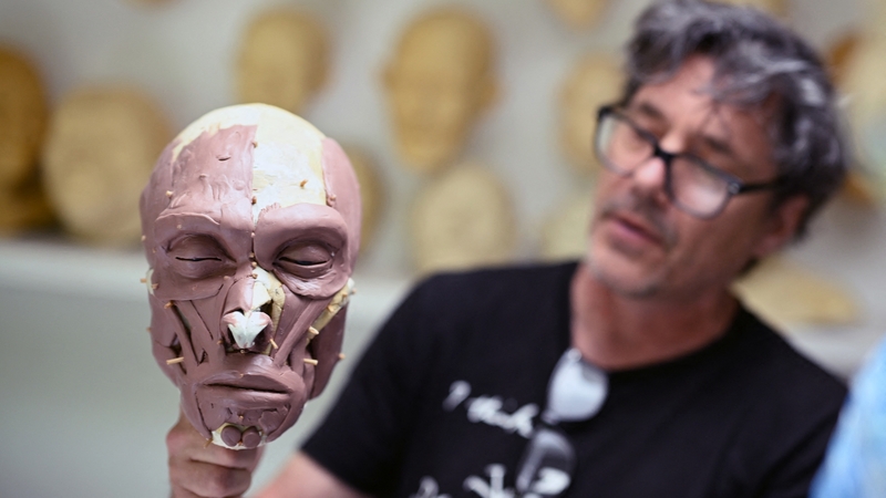 Dutch artist Alfons Kennis holds a model under construction representing a prehistoric human skull