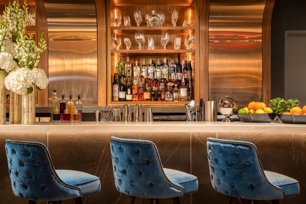 a bar with blue chairs and a shelf with bottles