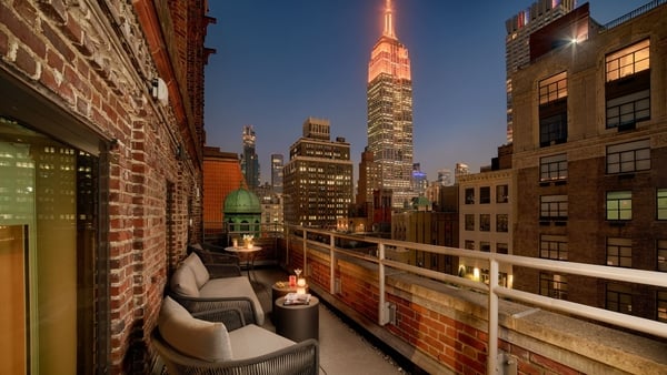 a rooftop patio with chairs and a tall building in the background