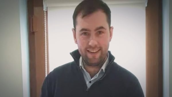 A man with black hair and a dark beard smiles into the camera
