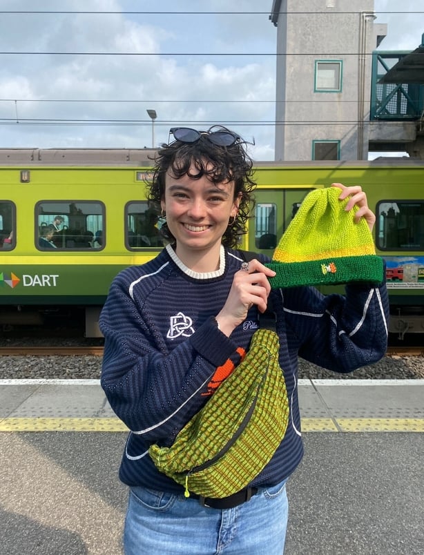 a person holding a green hat inspired by the DART, standing in front of the DART
