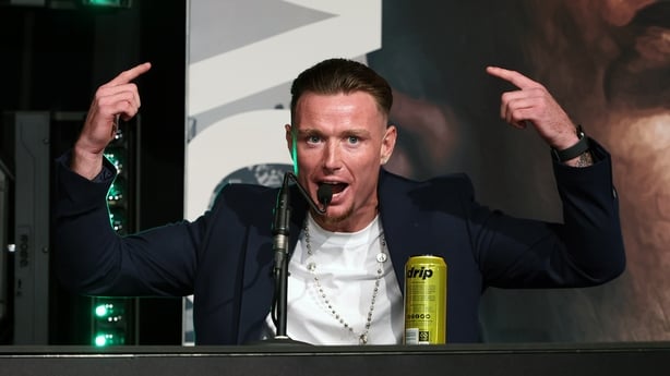 Paddy Donovan in a suit pointing at a microphone at press conference