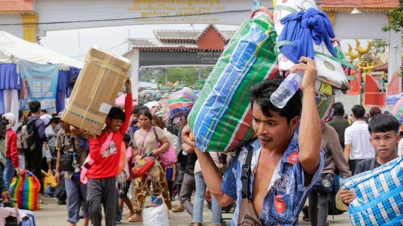 Cambodian migrant workers carry their belongings as they returned from Thailand through the Doung International Gate in Battambang province