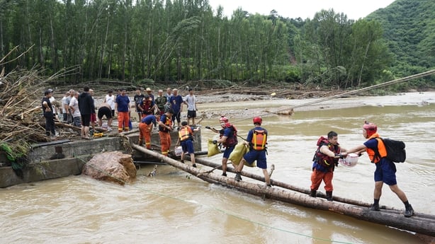 Firefighters transport supplies through a temporarily built wooden bridge at Liulimiao Town in Huairou District Beijing, China