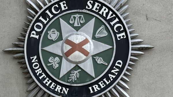 woman stands near sign for the police service of northern ireland