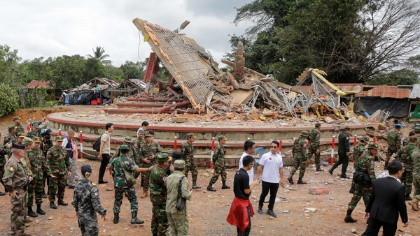Military attaches and diplomats next to a destroyed building by the An Ses border checkpoint in Cambodia's Preah Vihear province