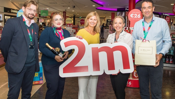 A group of people with a 2m sign at Cork Airport celebrating its 2 millionth passenger of 2025