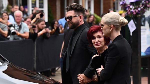 (L-R) Jack Osbourne, Sharon Osbourne, and Kelly Osbourne view tributes to the late Ozzy Osbourne from fans as his funeral cortège travels through his home city of Birmingham on 30 July, 2025