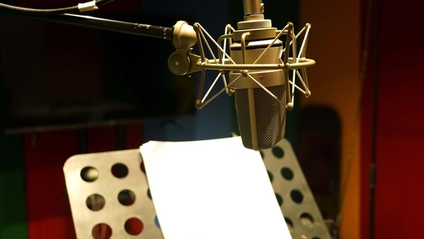 Close up a microphone in the recording studio, with scripts on a stand