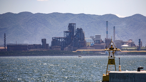 a body of water with a factory in the background