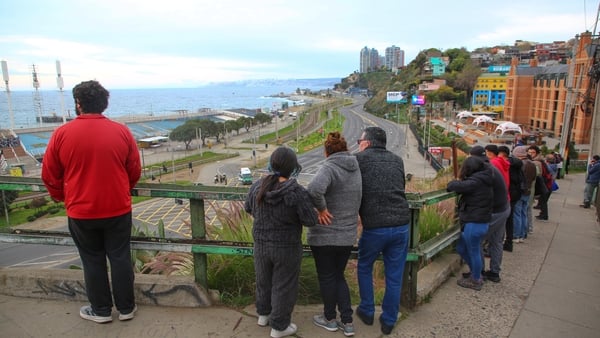a group of people standing on a ledge looking at the sea