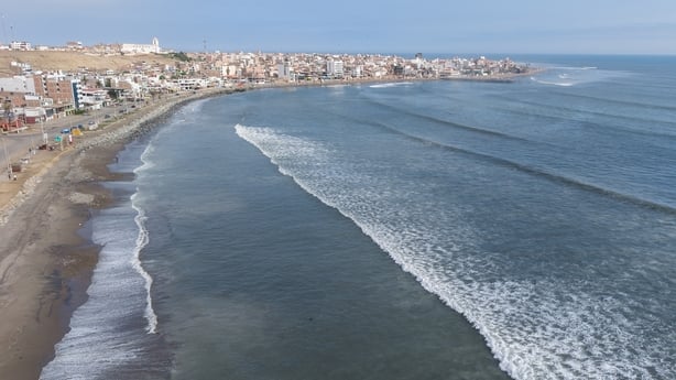 a beach with waves and buildings in the background