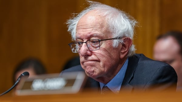 Image shows US politician Bernie Sanders sitting at a desk