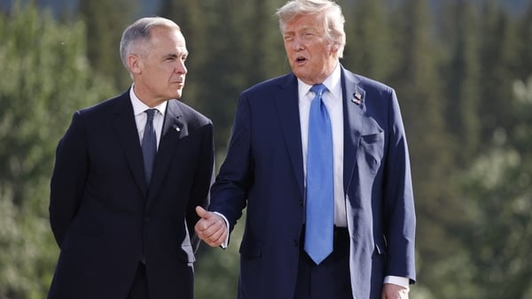 Mark Carney and Donald Trump walk side by side with trees in the background