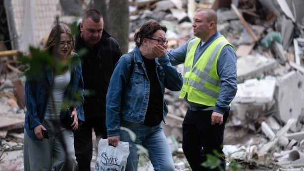 Two women and one man are upset as they walk past a destroyed building in Kyiv Ukraine