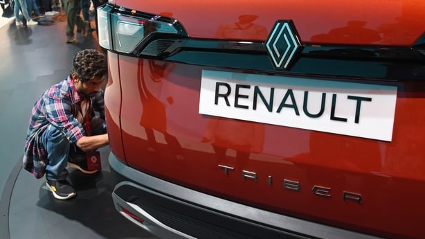 a person looking at a new red Renault car
