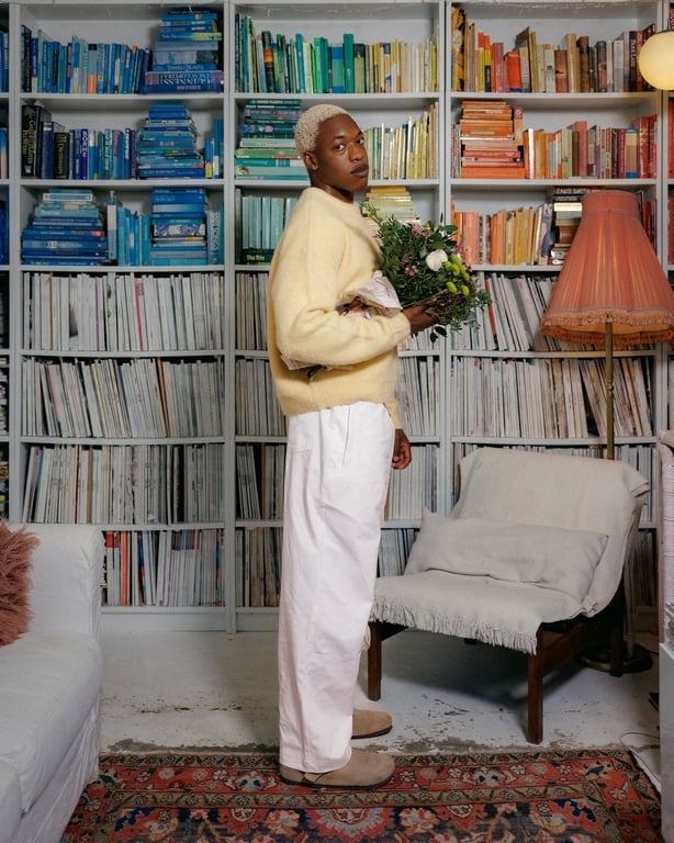a person holding flowers in front of a bookcase