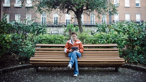 Young woman enjoying a day in park and reading from her digital tablet