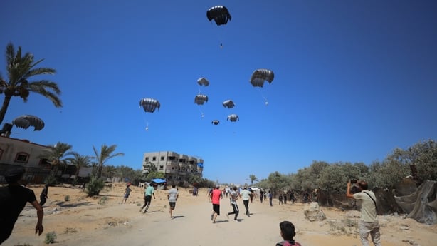 Palestinians gather to collect humanitarian aid dropped by parachute in the Al-Zawaida area of Deir al-Balah, Gaza