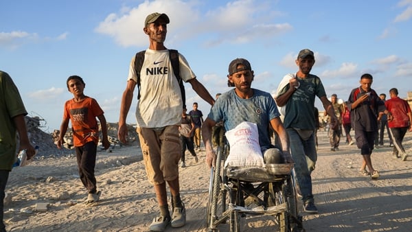 A male wheelchair user holds a bag of flour as Palestinians, struggling with hunger, receive limited amount of flour at humanitarian aid distribution point at Zikim border crossing in Gaza