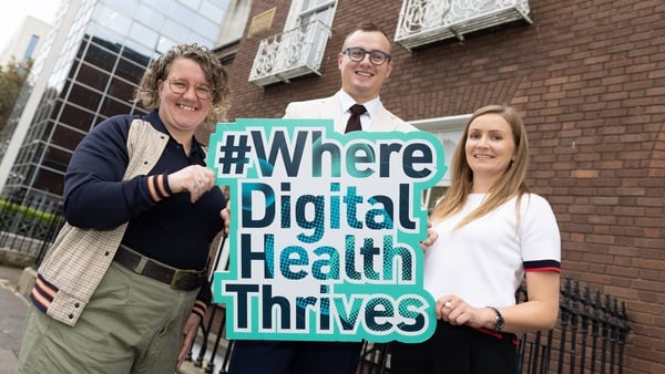 a group of people standing in front of a brick building holding a sign