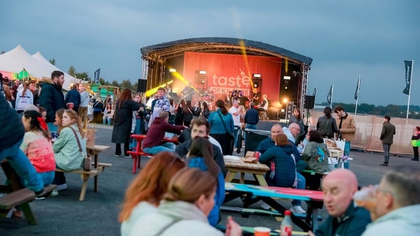 a group of people sitting at tables and chairs with a stage in the background