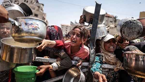 A young girl tries to get the attention of a charity distributing meals to Palestinians amid severe food shorages in Gaza