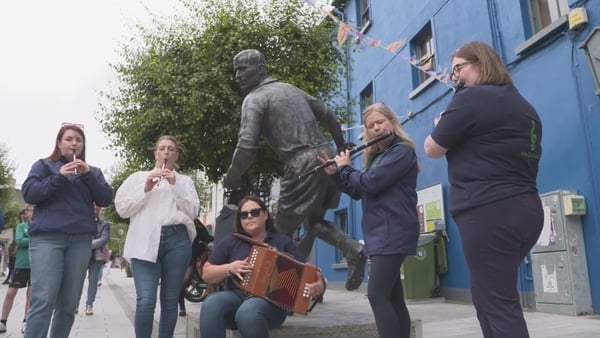People play music near a statue in Wexford Town during the Fleadh Cheoil