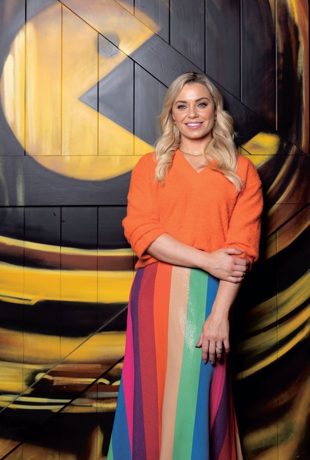 Anna Geary standing in front of a colorful wall