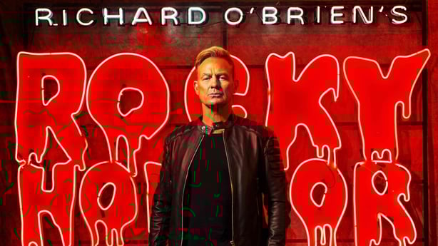 Jason Donovan in front of a neon Rocky Horror Show sign