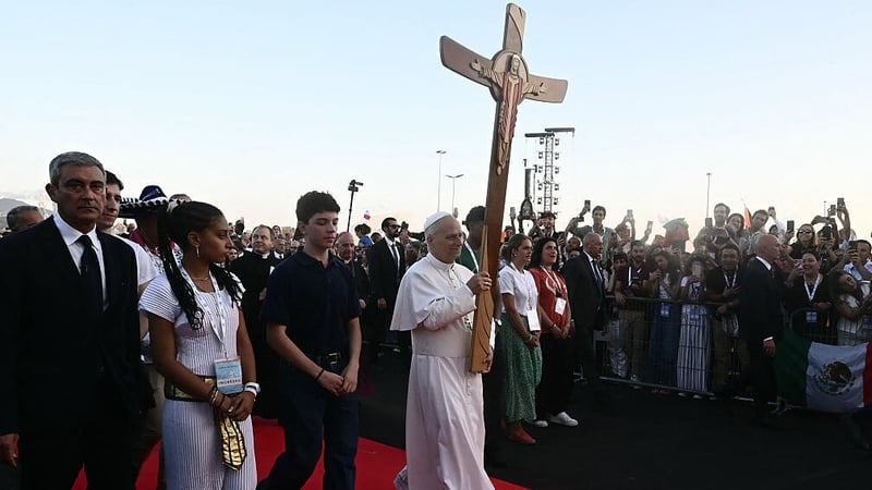 Pope Leo XIV holds a cross as he arrives in Rome before mass as part of the Jubilee of Youth