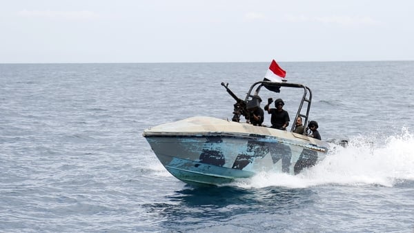 A small boat with people on board and a yemeni flag flying from it