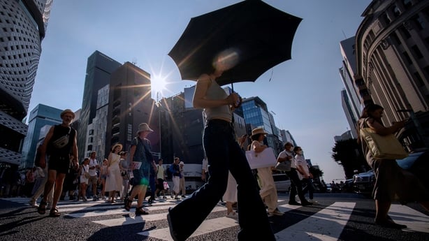 Sun shines down on people crossing a street in tokyo