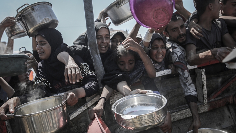 Palestinians try to collect free food from a charity kitchen in Gaza City